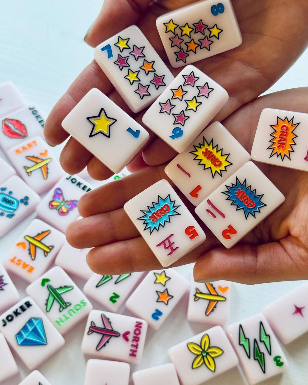 Colorful game pieces with various symbols held in a hand
