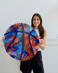 Load image into Gallery viewer, Person holding a colorful circular art piece with blue, orange, and red patterns against a white background

