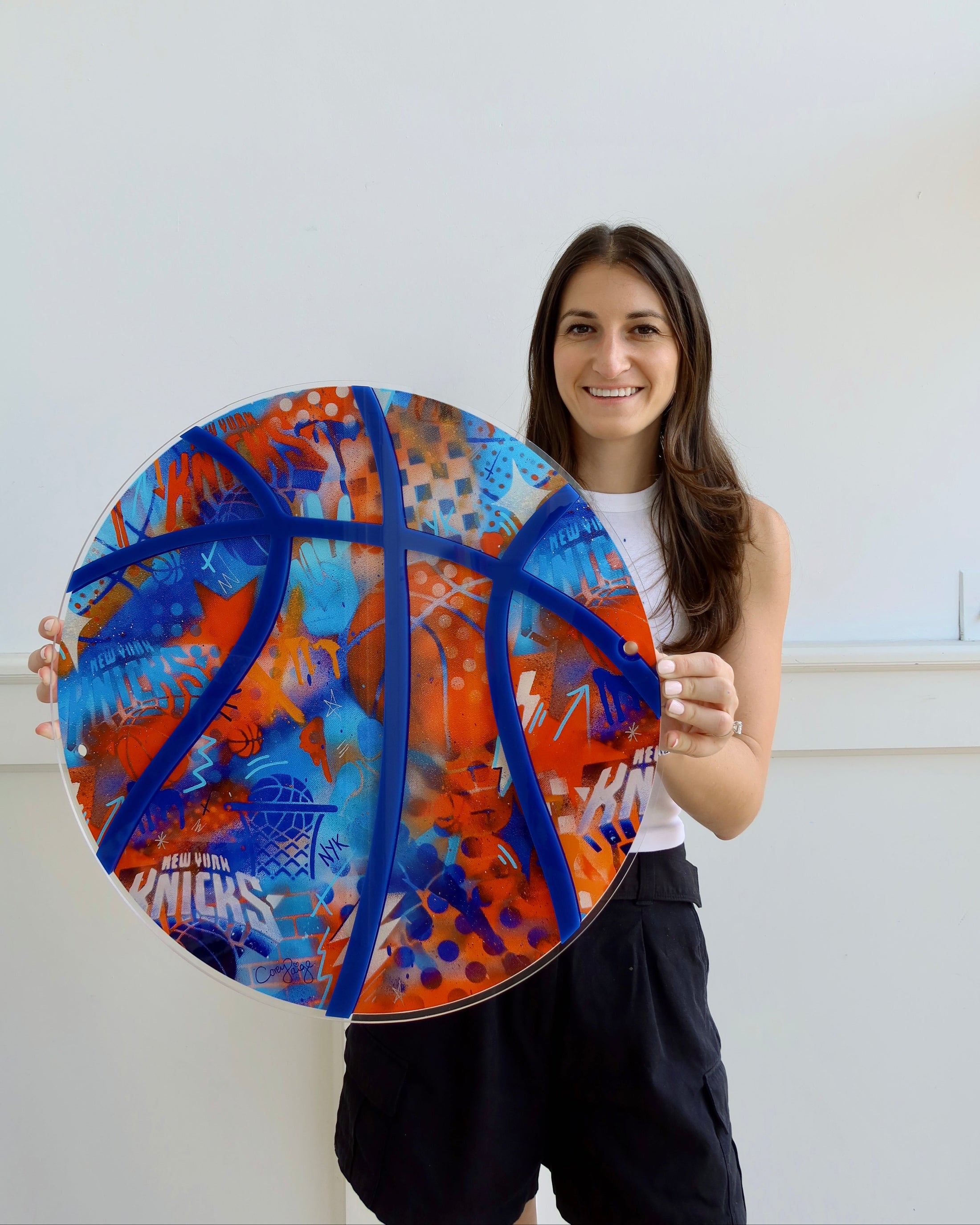 Person holding a colorful circular art piece with blue, orange, and red patterns against a white background