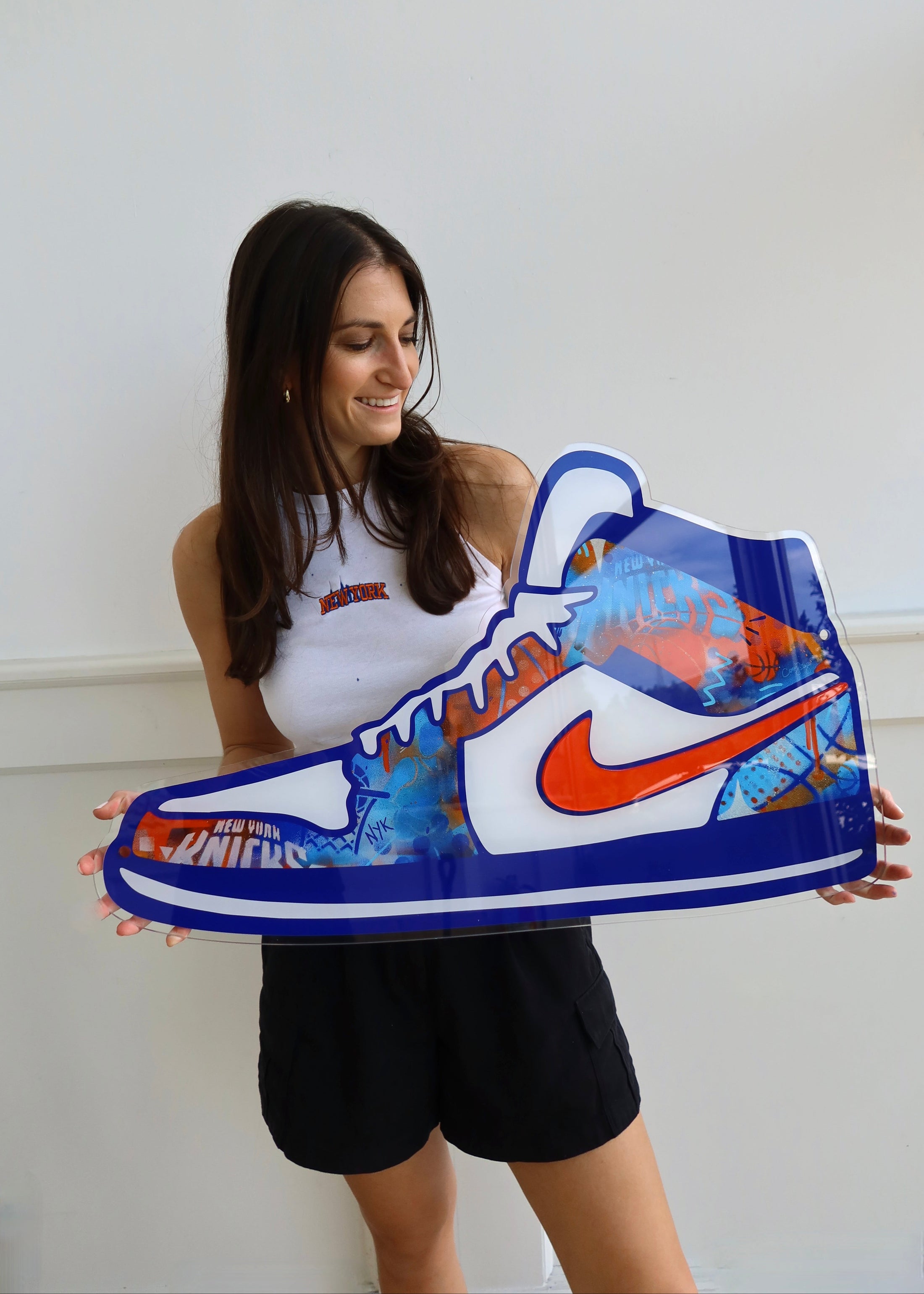 Woman holding a large inflatable sneaker with a colorful design and Nike logo.