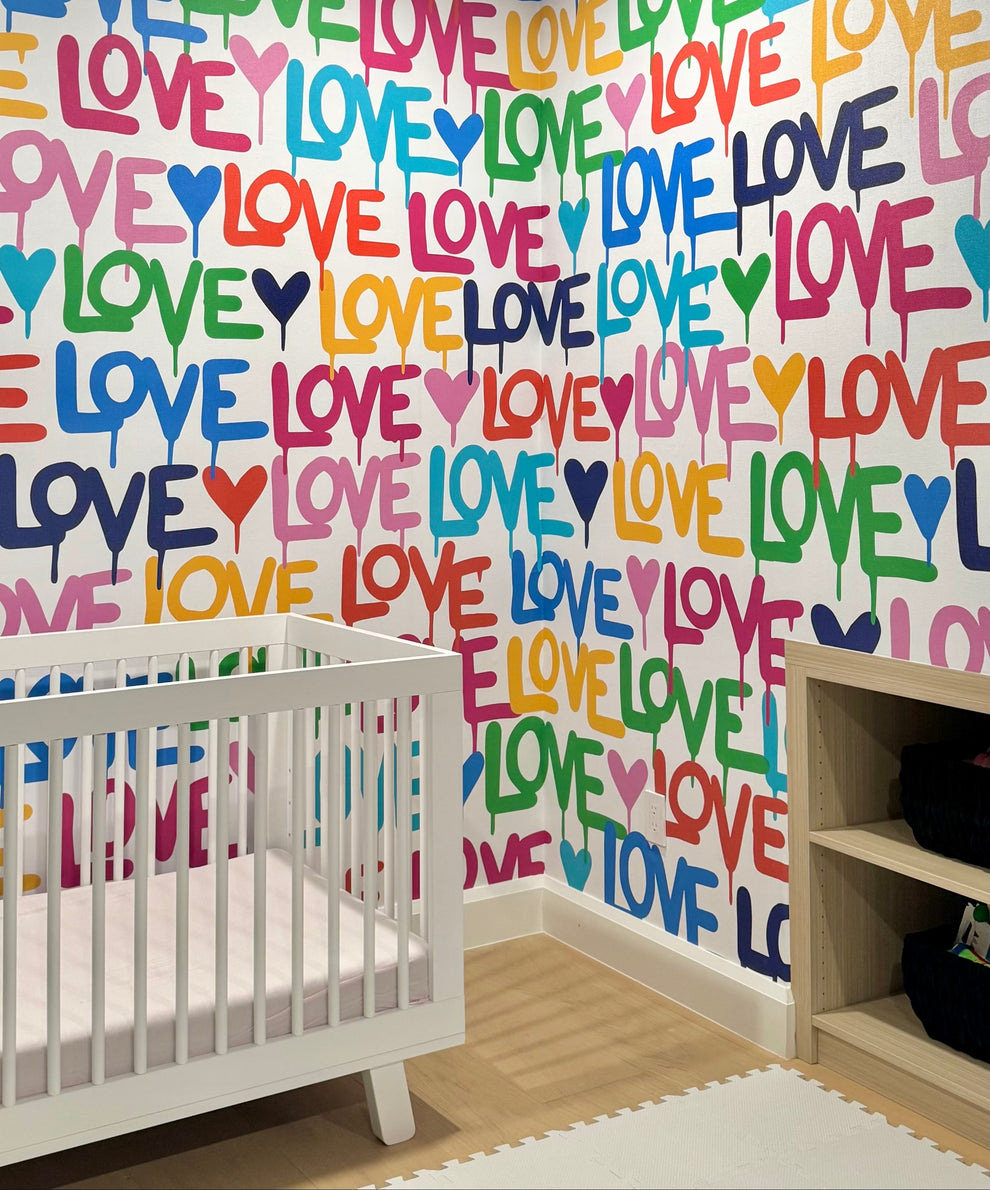 Nursery room with colorful 'LOVE' wallpaper and a white crib.